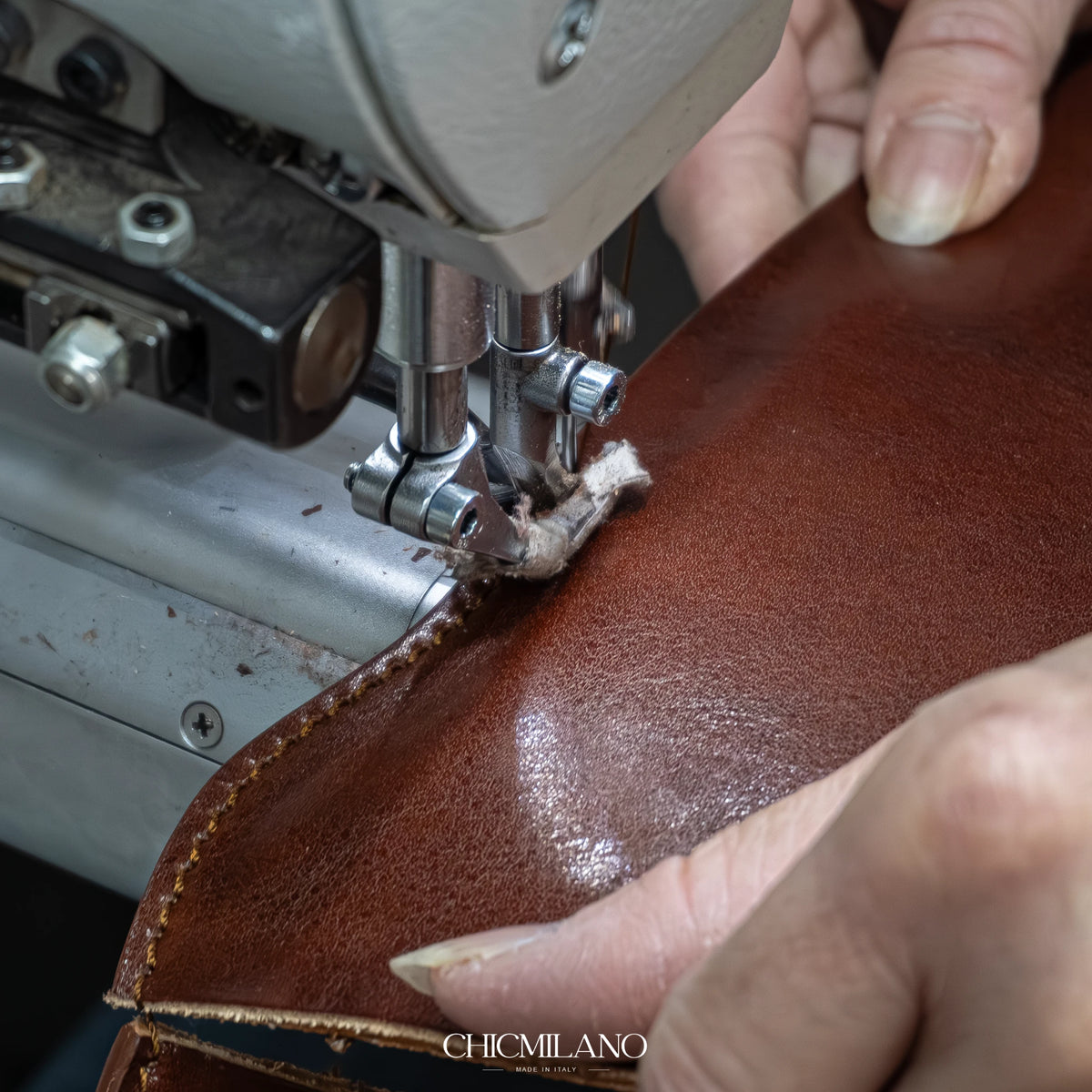 Illustrative close-up of an artisan stitching brown leather by hand
